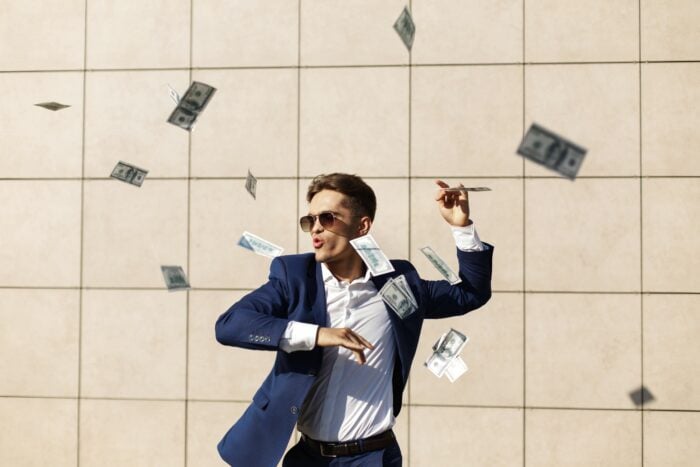 Young American businessman enjoying the lower cost of living in Mexico, dancing with USD bills.