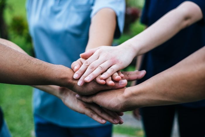 polyglots of different ethnicities stacking hands together