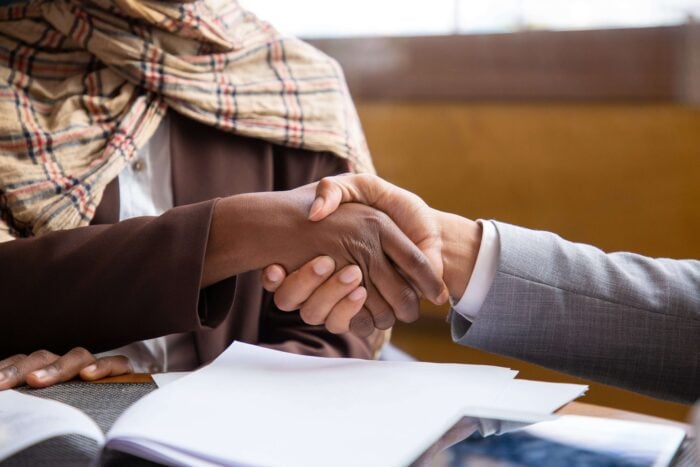 Two people shaking hands while using Arabic phrases