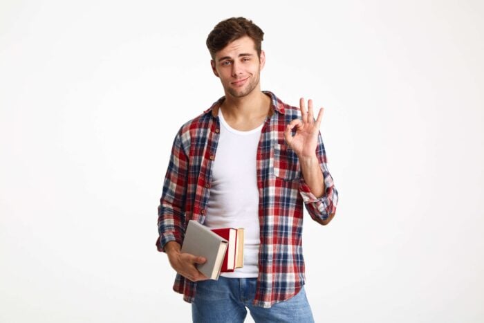 Young man carrying books and feeling confident for having an advanced English certificate.