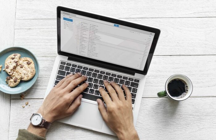 Man writing a work email in Spanish as he drinks a cup of coffee.