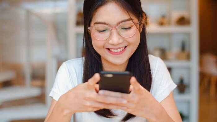 Young Asian woman writing an informal email in Spanish on her phone.