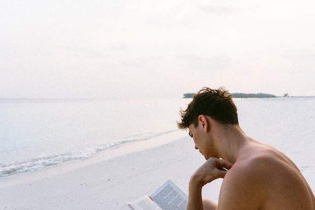 Young man reading on the beach