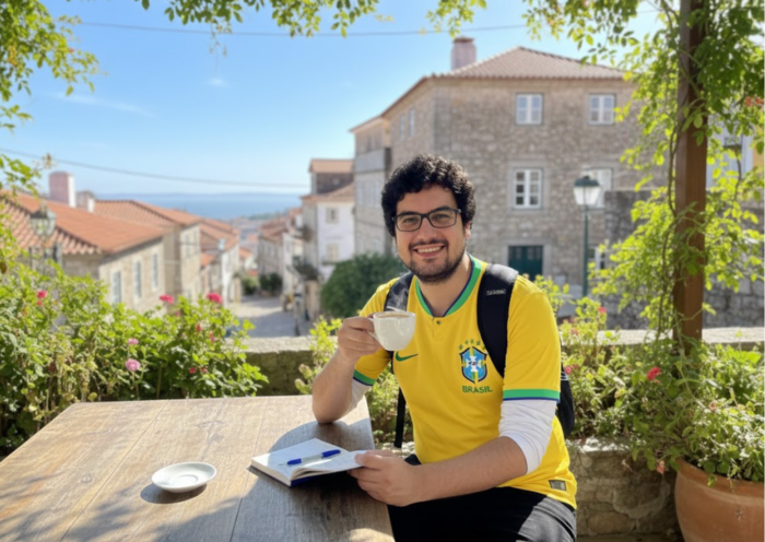 Portuguese learner practising with a notebook and coffee during a study trip in a historic Portuguese-speaking setting.