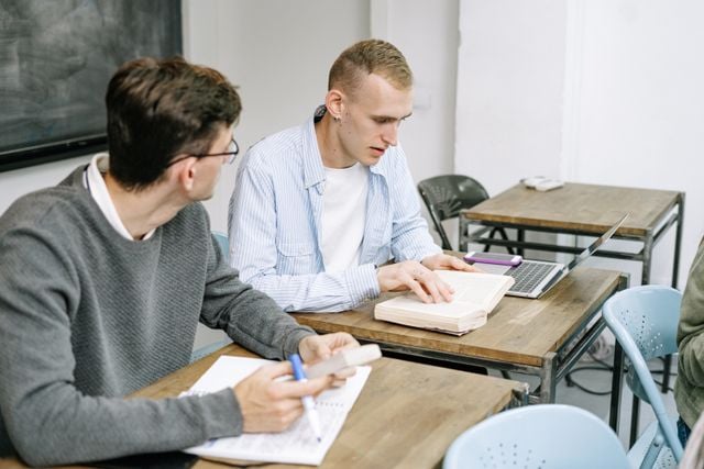 Two students studying Portuguese together in a classroom as part of a structured 6-month language learning plan.