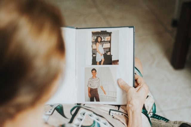 Person looking through old photographs, illustrating how the Spanish conditional can express probability or assumptions about past events.