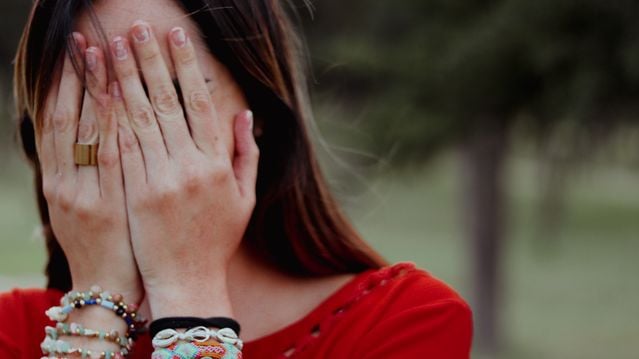 Woman covering her face in regret, illustrating how Spanish conditionals can express regret and imagined alternatives to past situations.