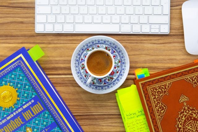 Turkish language books, notes, and coffee on a desk, illustrating the study of consonant softening and hardening in Turkish.