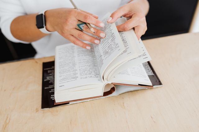 Hands flipping through a Spanish dictionary, representing the language reference work associated with the Real Academia Española.