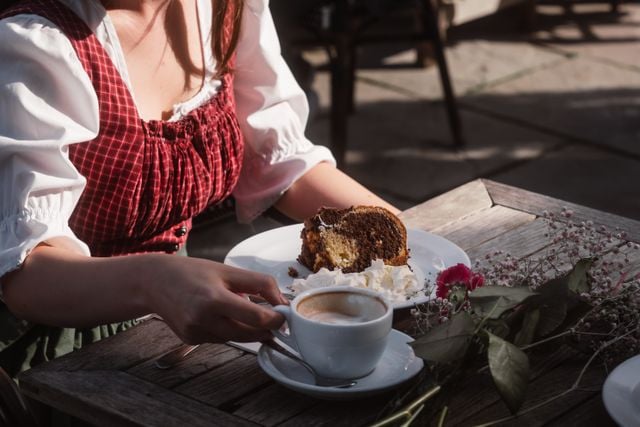 German woman enjoying coffee and cake at an outdoor café.