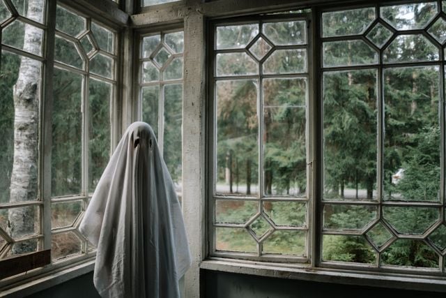Figure dressed as a ghost with a white sheet covering their body