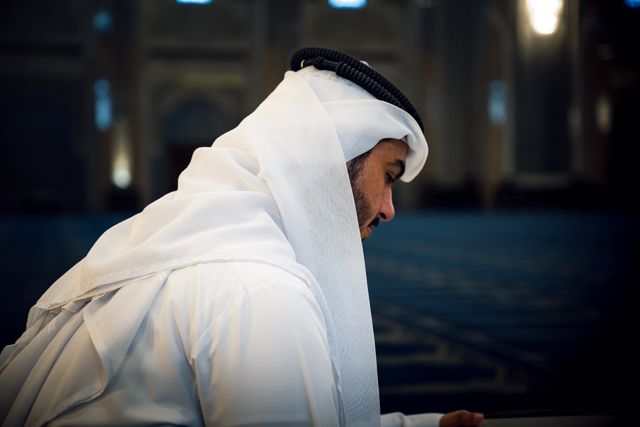 A man wearing traditional Arab clothing inside a mosque, illustrating the connection between Arabic language learning and religious study.